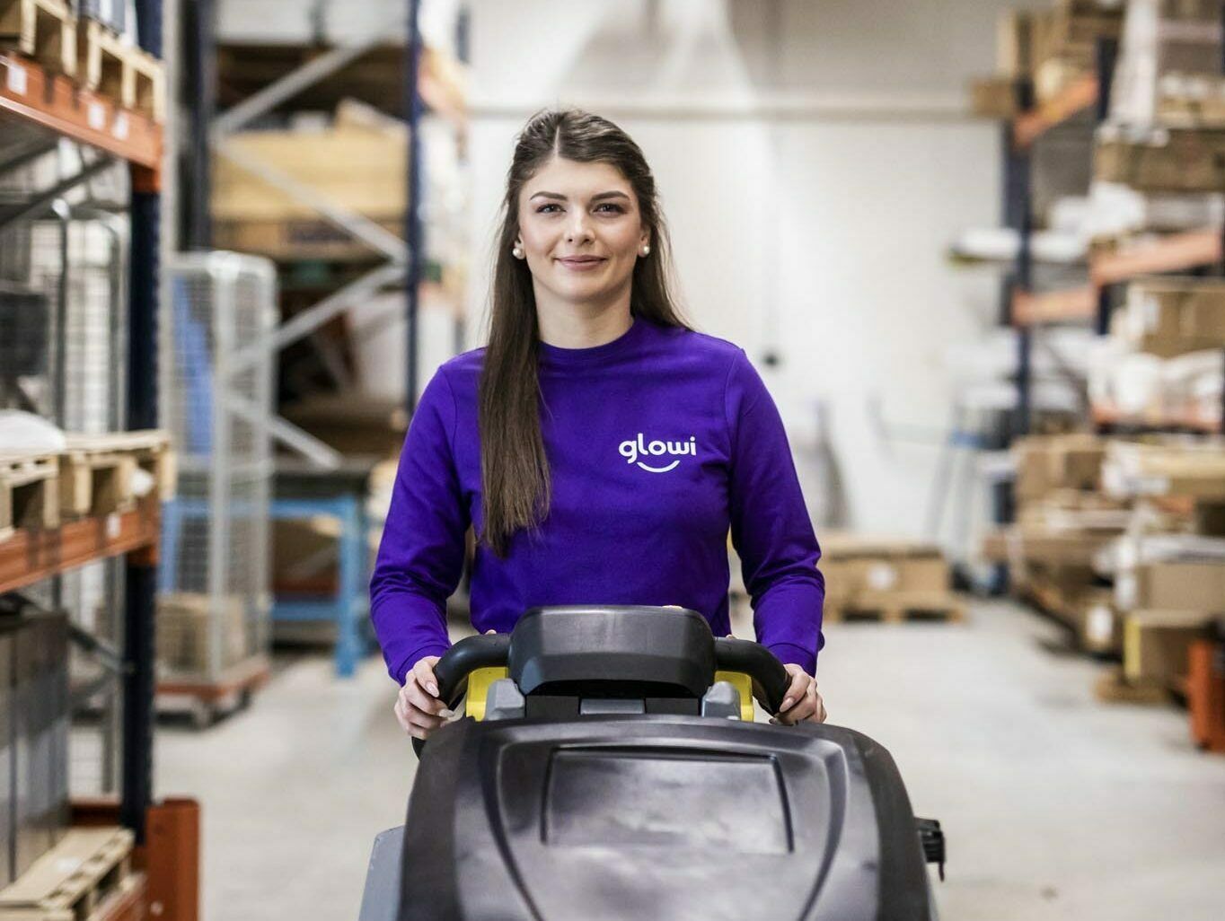 Schoonmaakster met schoonmaakmachine in de lens kijkend zoom portrait